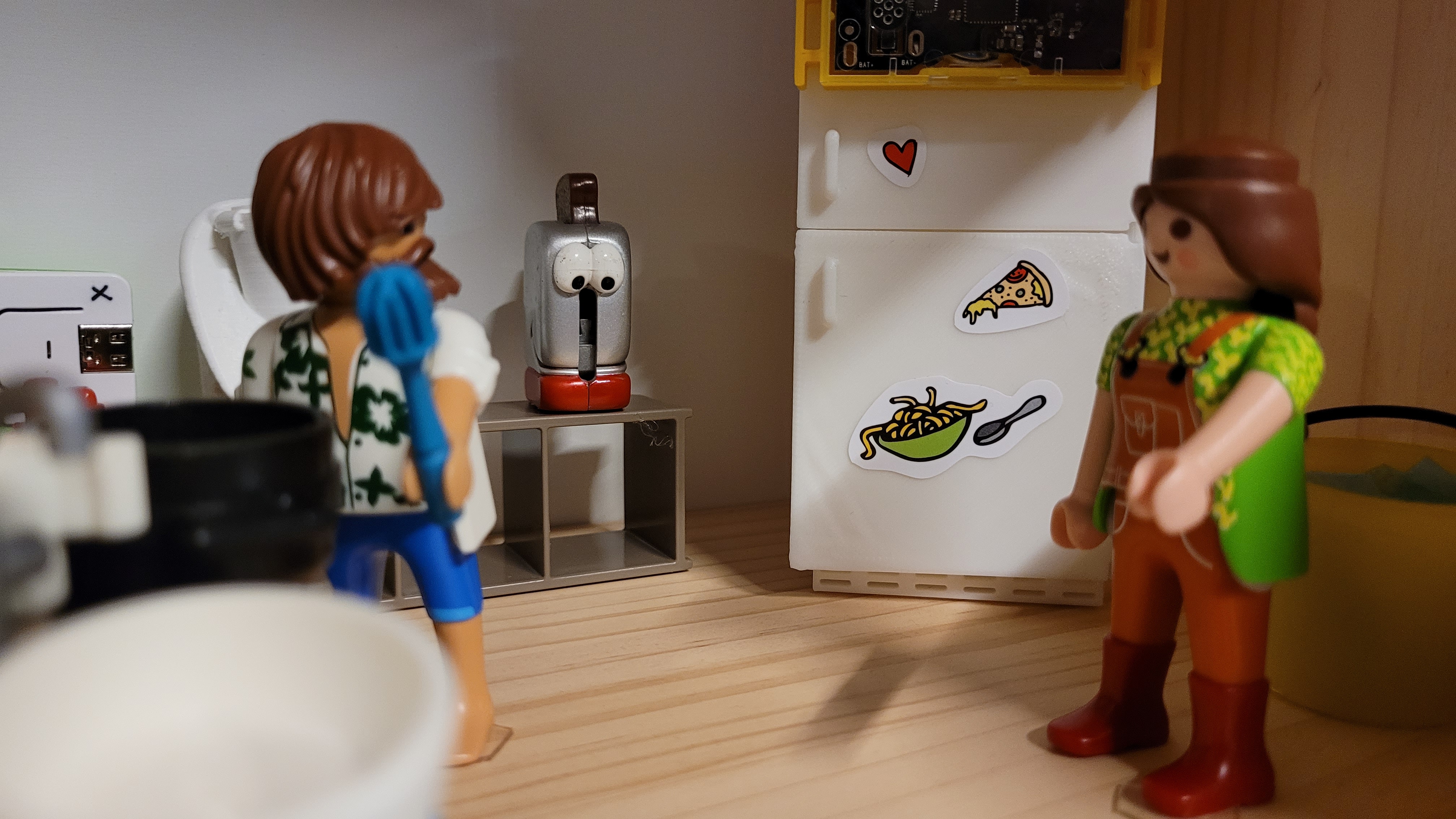 Modellküche mit zwei Playmobilfiguren und einem Kühlschrank mit Sensortag.