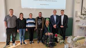 Nick, Tanja, Christin, Andy, Karola im Rollstuhl, Albrecht und Andreas vor einer Tafel